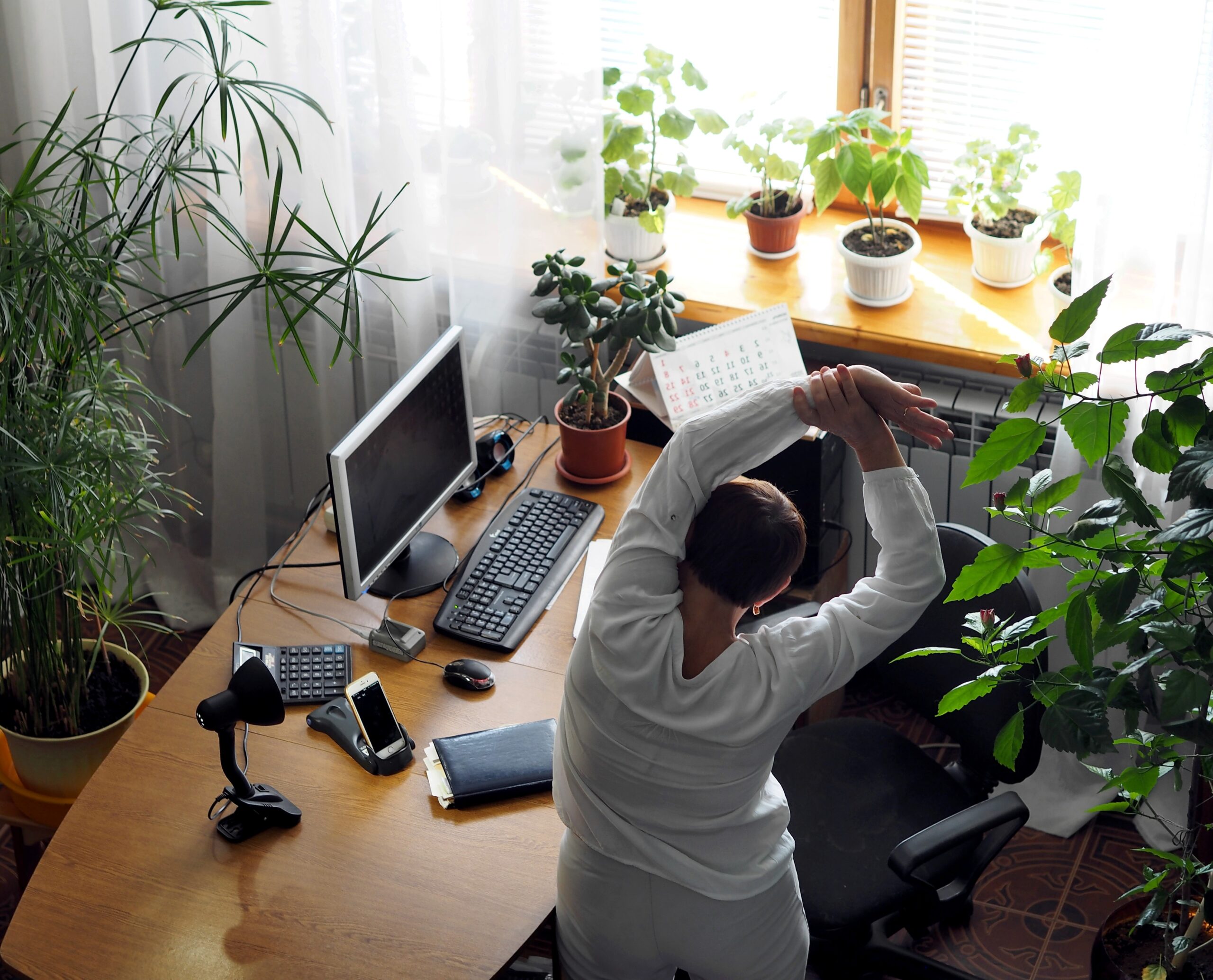An older woman warms up during a break from working online on a computer.